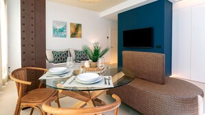 A modern dining area with a glass table, wooden chairs, and a blue accent wall. - Bright Apartment in the Heart of Seville Tom s de Ibarra II (Seville)