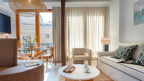 A modern living room with a round coffee table, a sofa, a chair, and a glass table with chairs. - Bright Apartment in the Heart of Seville Tom s de Ibarra II (Seville)