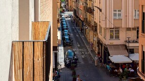 A narrow street lined with multi-story buildings, some with balconies and outdoor seating areas. - Cozy Central 2BD Apt in M Laga Trinidad Grund A (Málaga)