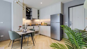 Une cuisine moderne avec des meubles blancs, un réfrigérateur en acier inoxydable et un coin repas comprenant une table et des chaises.