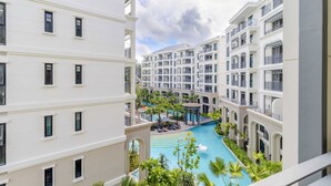Un hôtel moderne à plusieurs étages, doté d’une cour intérieure avec une piscine et entouré de verdure.