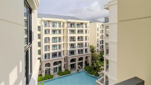 Un hôtel à plusieurs étages doté d’une cour intérieure abritant une piscine, des balcons et présentant une architecture moderne.