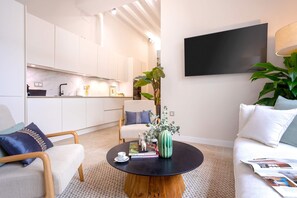 A modern living room with a round coffee table, a sofa, and a chair. A large plant is on the coffee table. - Luxury Apartment in Malaga Plaza del Obispo (Málaga)