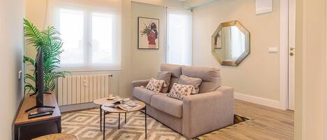 Una sala de estar con sofá, mesa de centro y una planta.