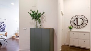Ein modernes Interieur mit einem grauen Schrank, einem runden Spiegel und einer kleinen Pflanze auf einer weißen Konsole.