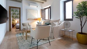 A modern living room with a sofa, armchairs, a coffee table, and a potted plant. - Exclusive Apartment in Granada Center Horno Marina 2 (Granada)