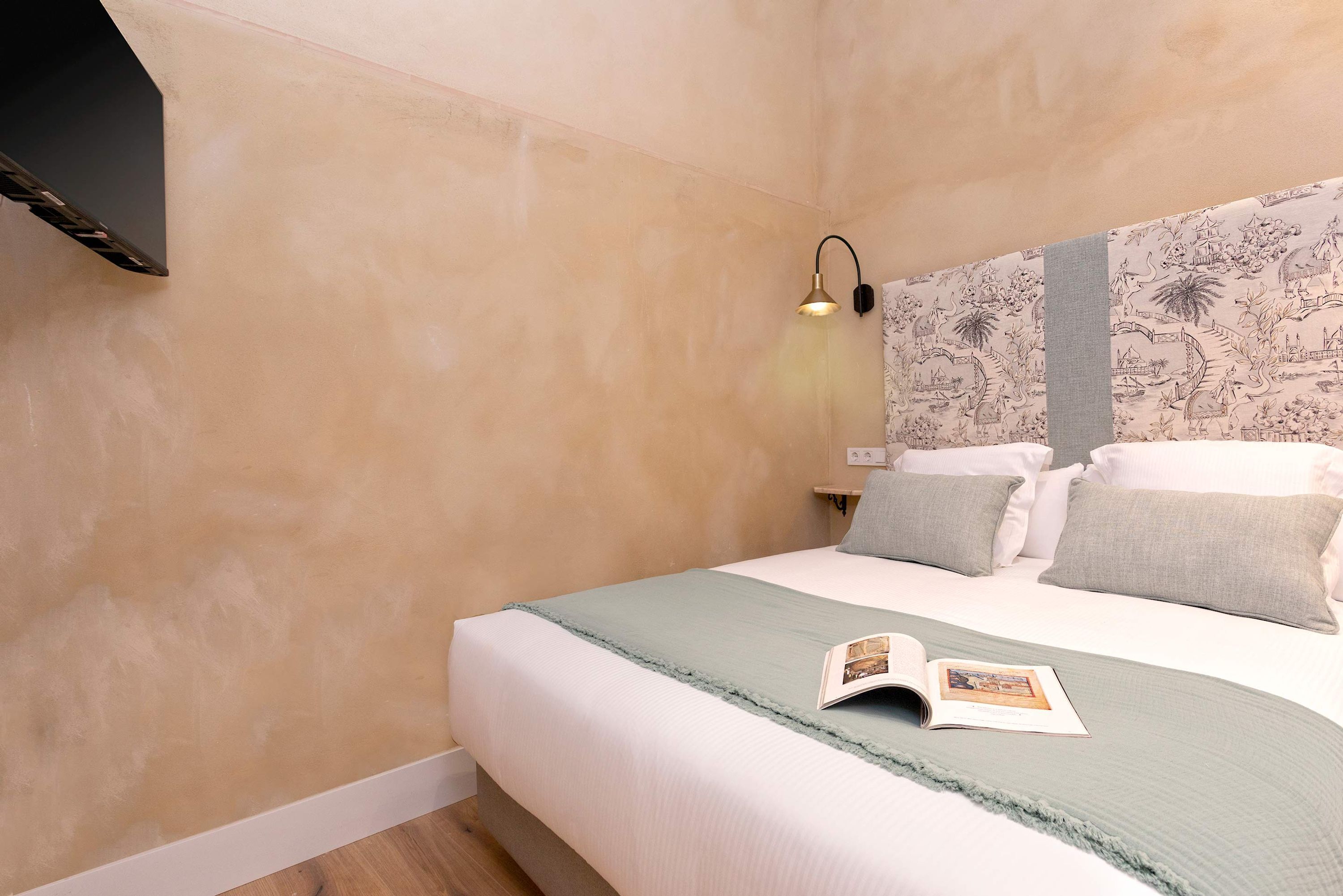 A bedroom with a bed, a nightstand, a lamp, and a wall with a mural.