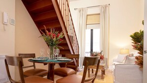 A dining area with a wooden table, chairs, and a vase of flowers. - Exclusive Apartment Near Cathedral Rodrigo Caro IV (Seville)