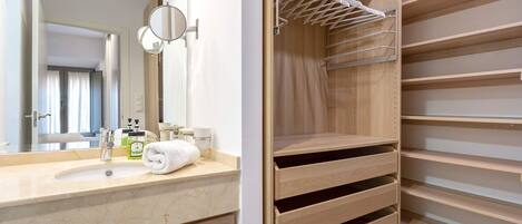A bathroom with a marble sink, a mirror, a towel, and a wooden closet with shelves.