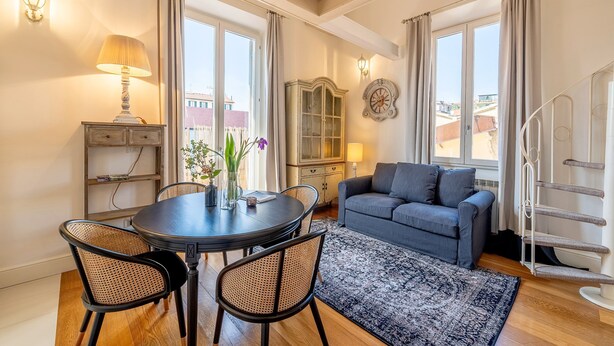 A living room with a round table, two chairs, a sofa, and a patterned rug. - Luxury Apartment in Florencia Scarlatti (Florence)