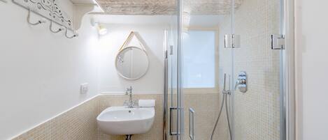 Un baño con cabina de ducha de vidrio, un lavabo y un espejo.
