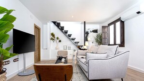 A modern living room with a sofa, a coffee table, a TV, and a staircase leading to another room. - Exclusive Apartment in Granada Horno Marina 11 (Granada)