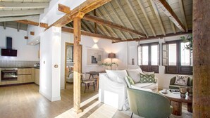 A spacious living area with a wooden ceiling, a sofa, a dining table, and a kitchen in the background. - Luxury Apartment in Granada Horno Marina 6 (Granada)