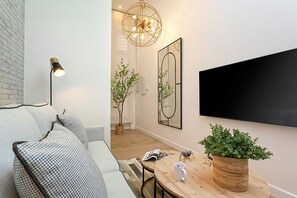 A modern living room with a sofa, a coffee table, a TV mounted on the wall, and decorative plants. - Luxury Loft in Granada Center La Paz II (Granada)