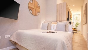 A modern bedroom with a large bed, a round wooden wall decoration, and a flat-screen TV mounted on the wall. - Luxury Loft in Granada Center La Paz II (Granada)