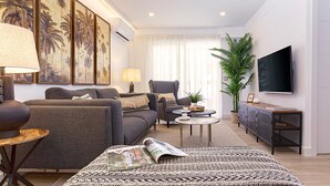 A modern living room with a sofa, armchair, coffee table, and a flat-screen TV. - Luxury Apartment in M Laga Victoria (Málaga)