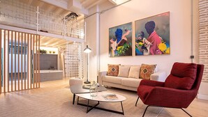 Un salon moderne avec un fauteuil rouge, un canapé blanc et deux tableaux accrochés au mur.