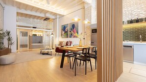 Un vaste espace de vie comprenant une table à manger en bois, des chaises et un canapé. Il y a également une cuisine équipée d’un lave-vaisselle et d’un plan de travail.