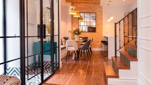 A modern interior with a wooden staircase, a dining area with chairs and a table, and a large mirror on the wall. - Exclusive Sevillian House With Terrace Casa San Lorenzo (Seville)