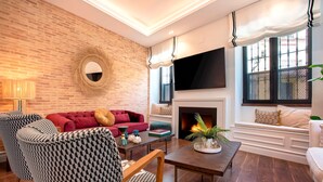 A living room with a brick wall, a fireplace, a TV, and a sofa. - Exclusive Sevillian House With Terrace Casa San Lorenzo (Seville)