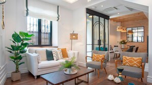 A modern living room with a white sofa, patterned armchairs, a coffee table, and a large plant. - Exclusive Sevillian House With Terrace Casa San Lorenzo (Seville)