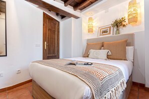 A bedroom with a large bed, a wooden door, and a wall-mounted light fixture. - Luxury House in Granada Center Reyes II (Granada)