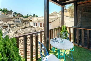 A balcony with a table and chairs, overlooking a town with traditional buildings. - Luxury House in Granada Center Reyes II (Granada)