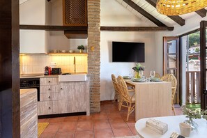 A kitchen with a built-in dishwasher, a dining area with a table and chairs, and a TV mounted on the wall. - Luxury House in Granada Center Reyes II (Granada)