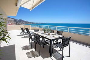 A terrace with a table set for dining, chairs, and a view of the sea. - Exclusive Penthouse in Fuengirola Beach Corales (Fuengirola)
