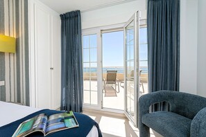 A hotel room with a bed, a reading area with a magazine, a chair, and a balcony with a view of the sea. - Exclusive Penthouse in Fuengirola Beach Corales (Fuengirola)
