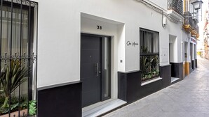 A modern building with a black and white facade, numbered 3B, featuring a dark door, metal balcony railings, and a small step leading to the entrance. - Lovely Apartment in Seville Center Lagar I (Seville)