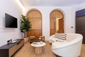 A modern living room with a flat-screen TV, a round coffee table, a sofa, and a potted plant. - Lovely Apartment in Seville Center Lagar I (Seville)