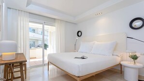 A modern hotel room with a large bed, a bedside table with a lamp, a small round table with a lamp, and a view of the outside balcony. - Bright Apartment Front of Beach Guadalmansa Beach (Estepona)