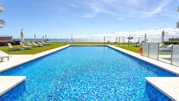 A rectangular swimming pool with clear blue water, surrounded by white tiled edges. - Bright Apartment Front of Beach Guadalmansa Beach (Estepona)