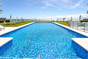 Una piscina rettangolare con acqua cristallina e bordi in piastrelle bianche.
