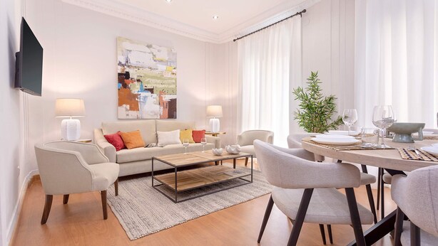 A modern living room with a sofa, coffee table, and dining area.