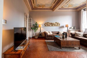 A living room with a television, sofas, a coffee table, and a decorative wall piece. - Luxury River View Apartment Biblioteca Nazionale (Florence)