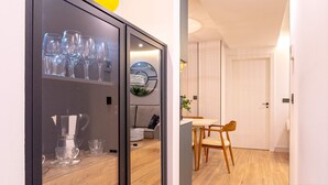 Moderni keittiö, jossa on sisäänrakennettu kaappi, kahvinkeitin sekä ruokailutila pöytineen ja tuoleineen.