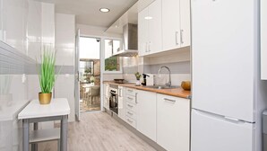 Una cocina moderna con armarios blancos, un lavamanos de acero inoxidable y un horno empotrado.