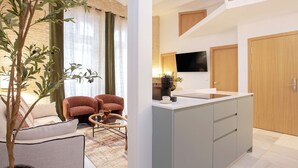A modern apartment with a living area featuring a sofa, a coffee table, and a potted plant. The kitchen includes a sink, a countertop, and a television mounted on the wall. - Cozy 3BD Duplex in Seville Center Gran Poder II (Seville)