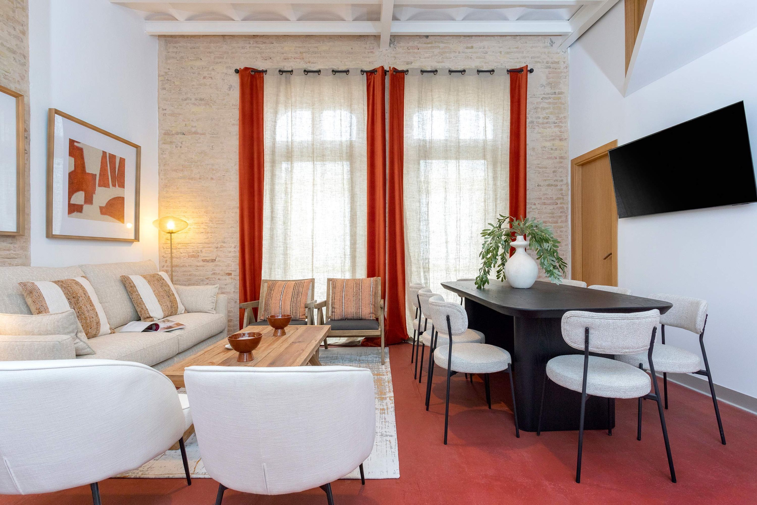 Un salon moderne comprenant un canapé, des fauteuils, une table basse et un coin repas avec une table et des chaises.