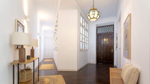 A hallway with a wooden bench, a lamp, and a woven basket on a console table. - Luxury Apartment in Malaga Larios VI (Málaga)