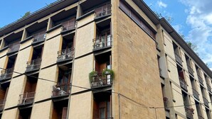 Um edifício de vários andares com varandas, uma fachada comercial com a sinalização 'BNL' e uma faixa de pedestres.