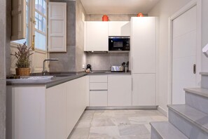 A compact kitchen with white cabinets, a microwave, and a sink. - Luxury Apartament in Seville San Isidoro II (Seville)