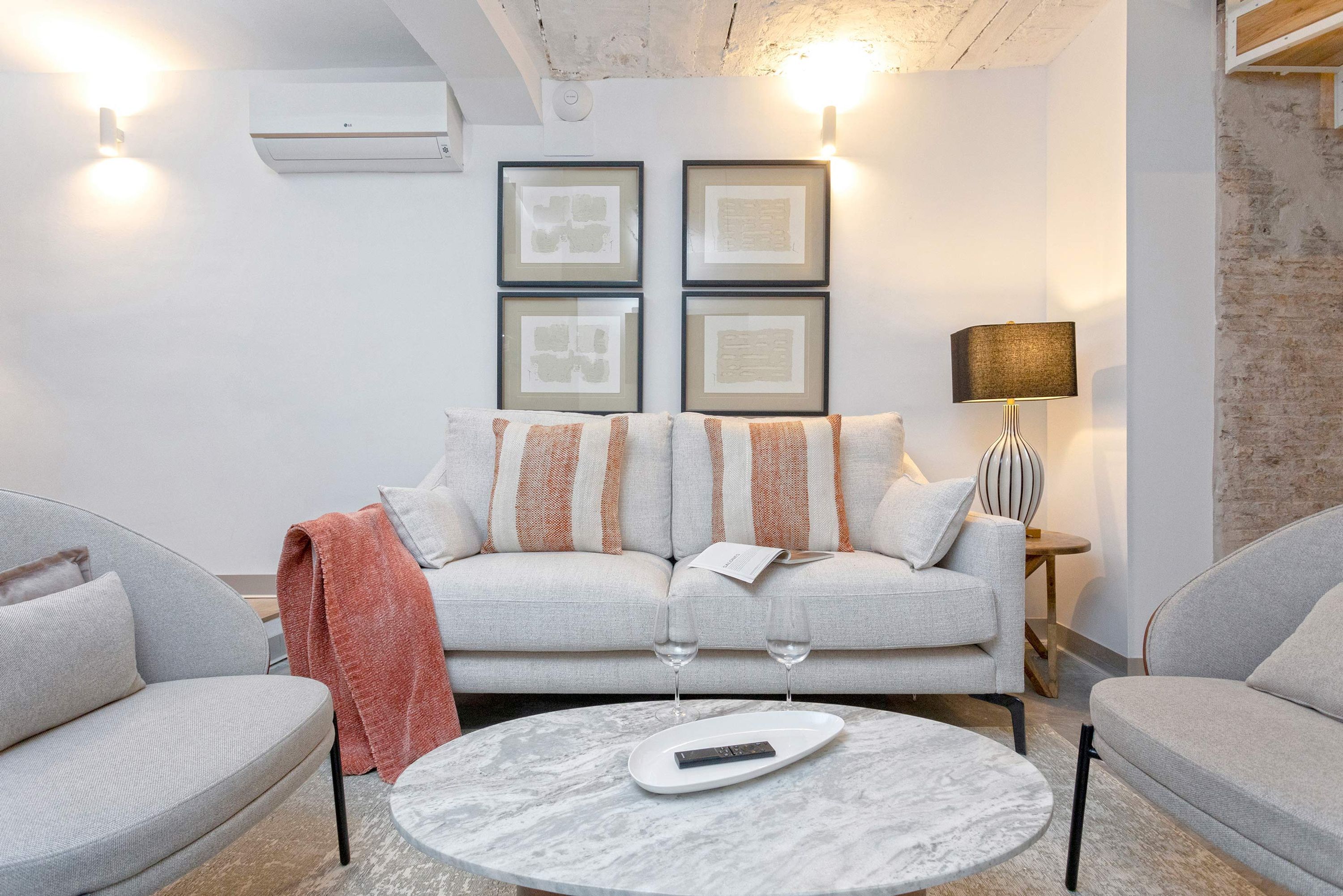 Un salon moderne avec un canapé gris, une table basse ronde et une lampe.