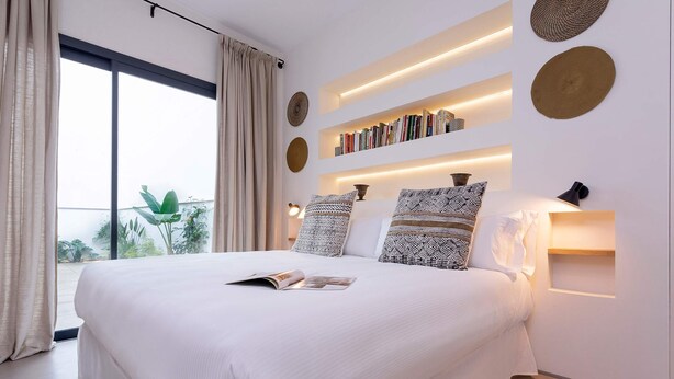 A modern bedroom with a large bed, bookshelves, and a view of greenery outside. - Lovely Apartment in Seville Pureza (Seville)