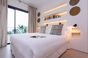 Camera da letto moderna con un letto grande, scaffali e vista su un'area verde.