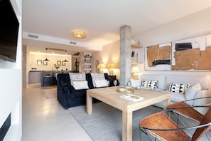 A modern living room with a dining table, sofas, and a kitchen in the background. - Lovely Apartment in Seville Pureza (Seville)