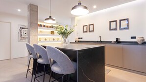 A modern kitchen with a central island, bar stools, pendant lighting, and a minimalist design. - Lovely Apartment in Seville Pureza (Seville)