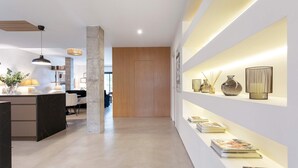 A modern interior with a central wooden door, a reception desk with a lamp, and a shelf with decorative items. - Lovely Apartment in Seville Pureza (Seville)